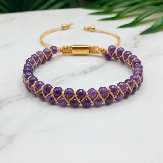 Purple Amethyst beaded gemstone adjustable bracelet with gold accents on a marble surface 