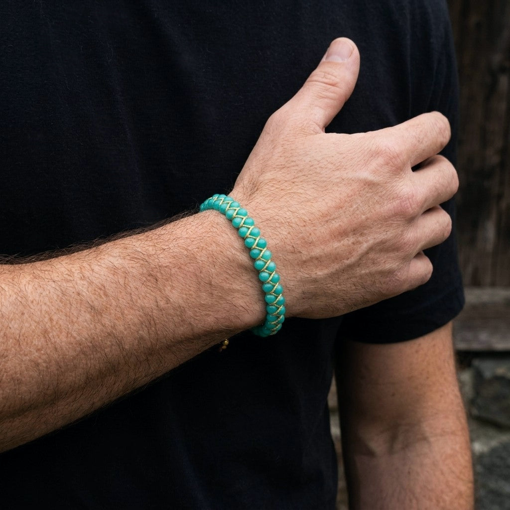 A man wearing a teal braided Amazonite bracelet on a black background