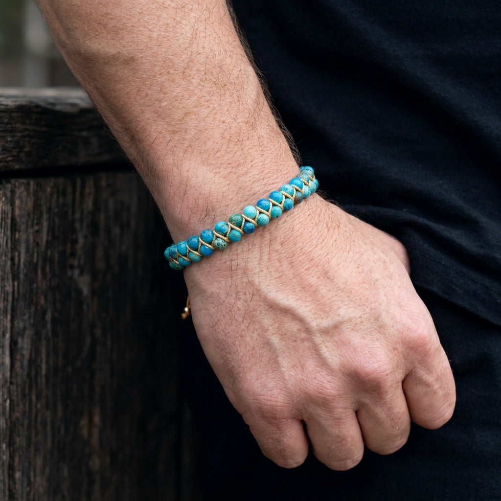 Blue sea sediment jasper beaded gemstone bracelet with gold accents on a man's wrist
