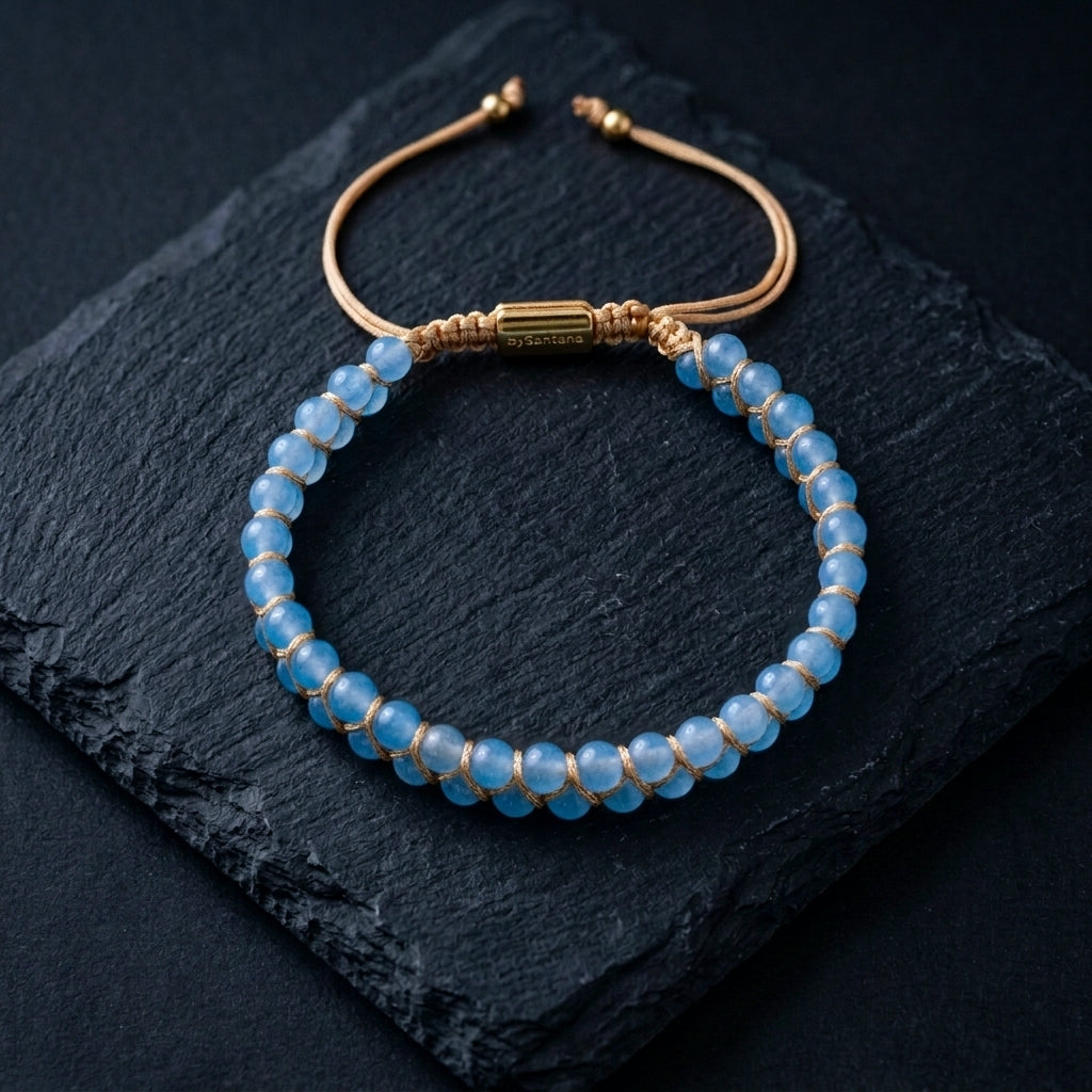 Blue aquamarine beaded gemstone bracelet with gold accents on a dark stone surface