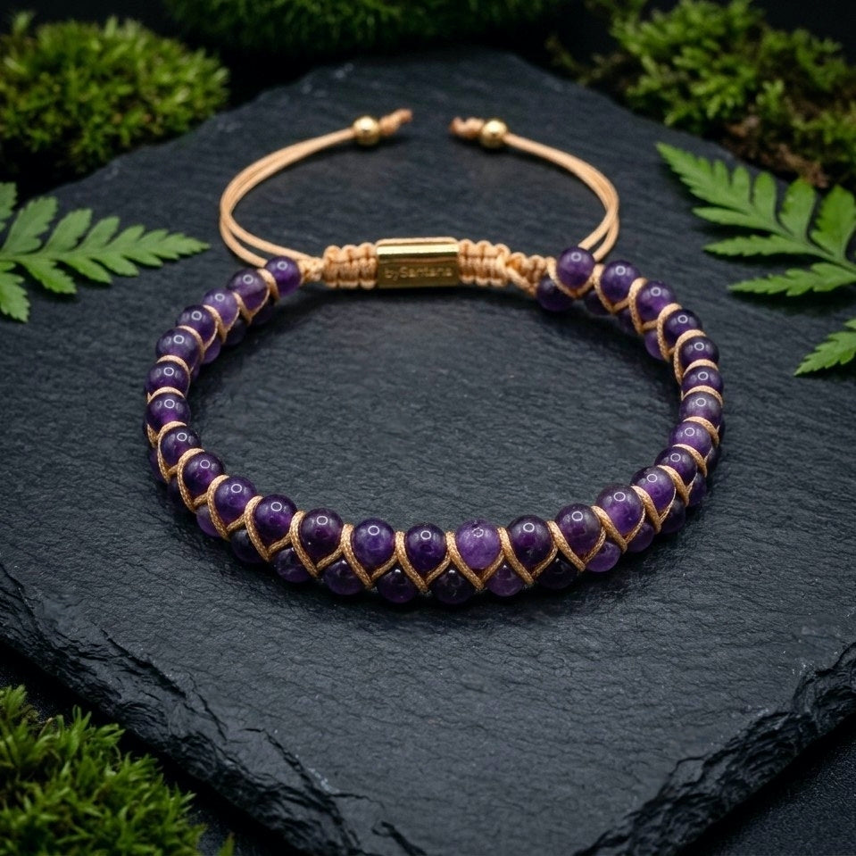 Purple Amethyst beaded gemstone adjustable bracelet with gold accents on a dark stone surface 