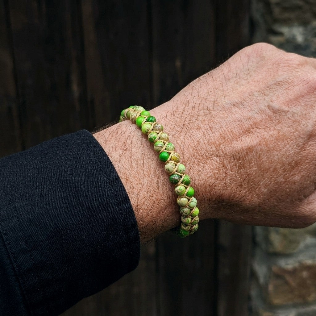 Green jasper beaded bracelet on a man's wrist with a blurred background