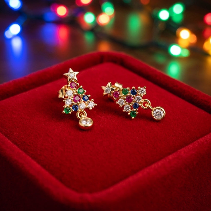 A pair of gold-toned dangle earrings decorated with colorful gemstones and clear crystals, displayed on a red velvet jewelry box with blurred festive lights in the background.