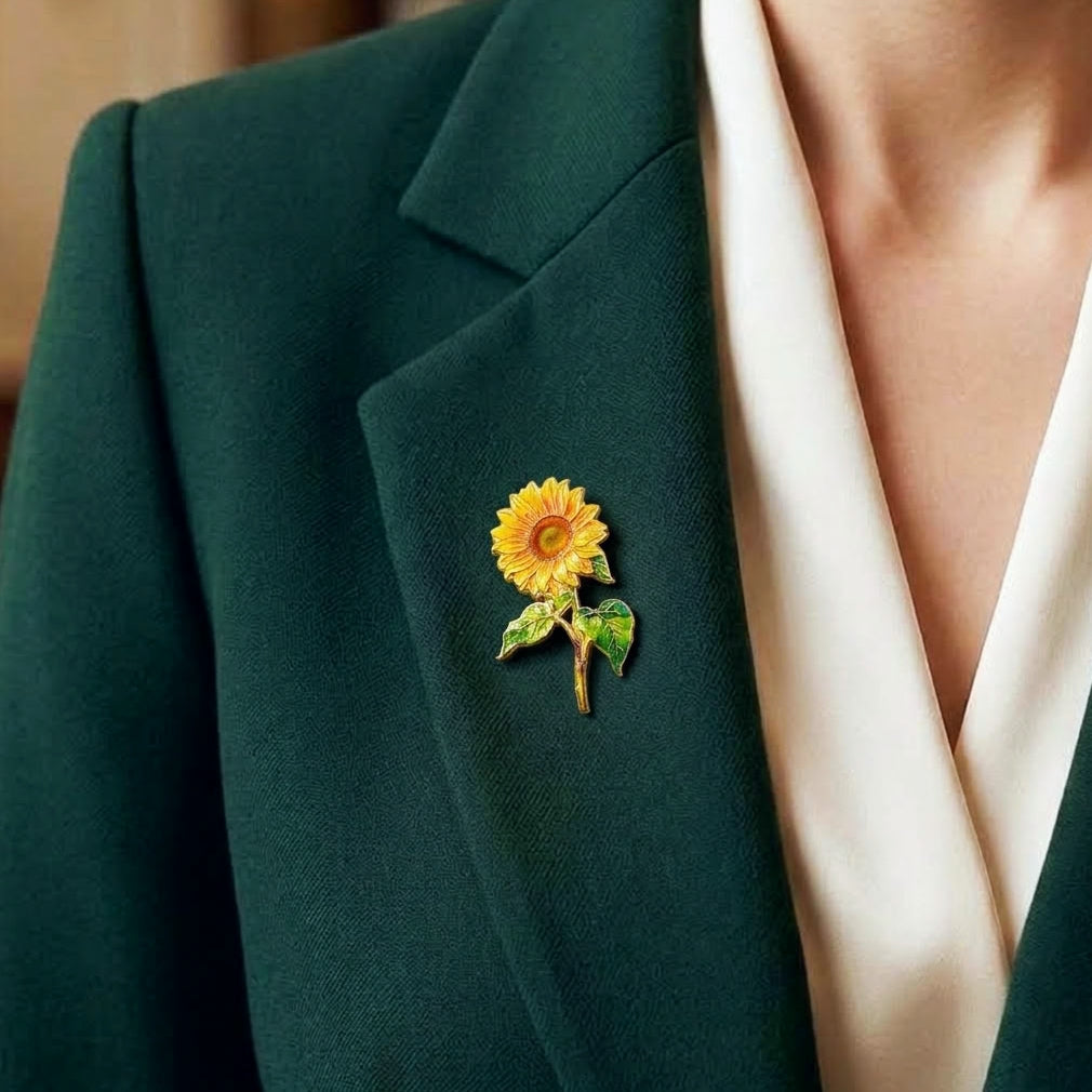 A close-up of a person wearing a dark green blazer over a cream-colored top, featuring a small yellow sunflower lapel pin on the left lapel.