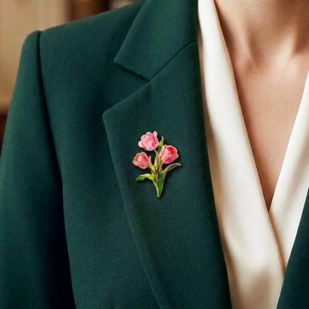 A close-up of a person wearing a dark green blazer over a cream-colored top, featuring a small pink tulip and green floral enamel pin on the lapel.