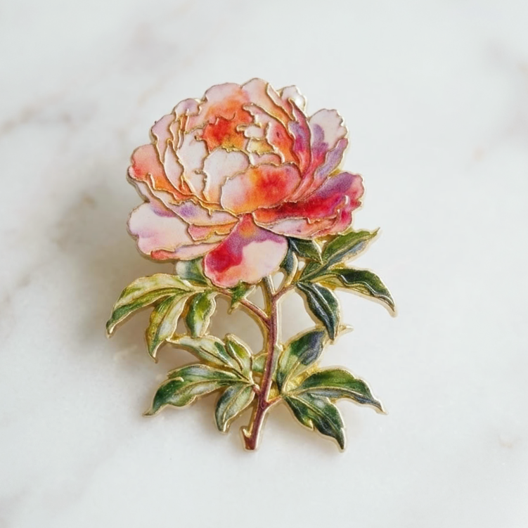 An enamel pin of a peony flower on a white marble background.