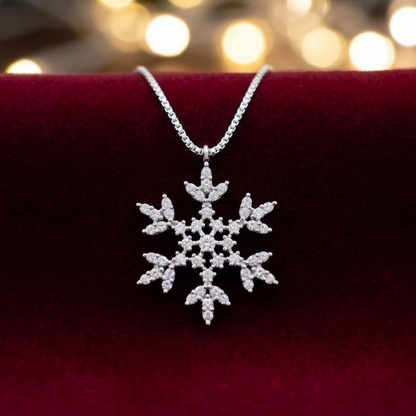 A 925 silver snowflake pendant necklace adorned with micro pave sparkling clear cubic zirconia stones and a venetian box chain, resting on a deep red velvet surface with a warm, blurred festive holiday background.