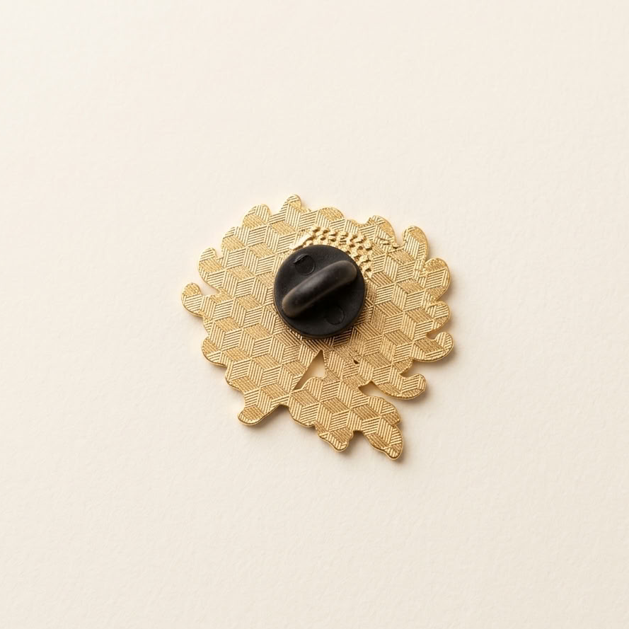 The back of an enamel pin with a black rubber back, shown on a light cream textured background.