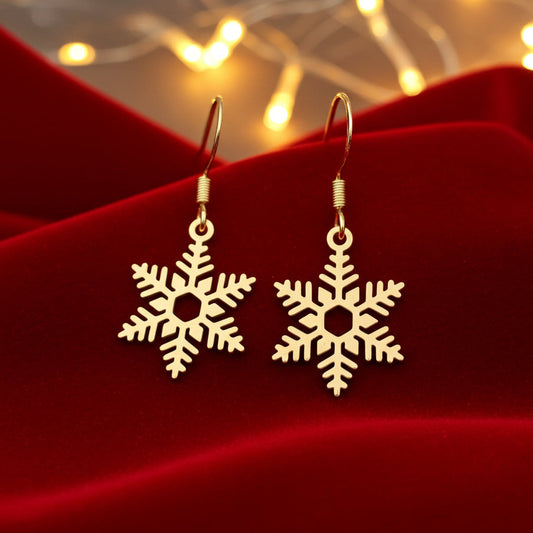 Gold snowflake earrings on a red fabric background with blurred Christmas lights