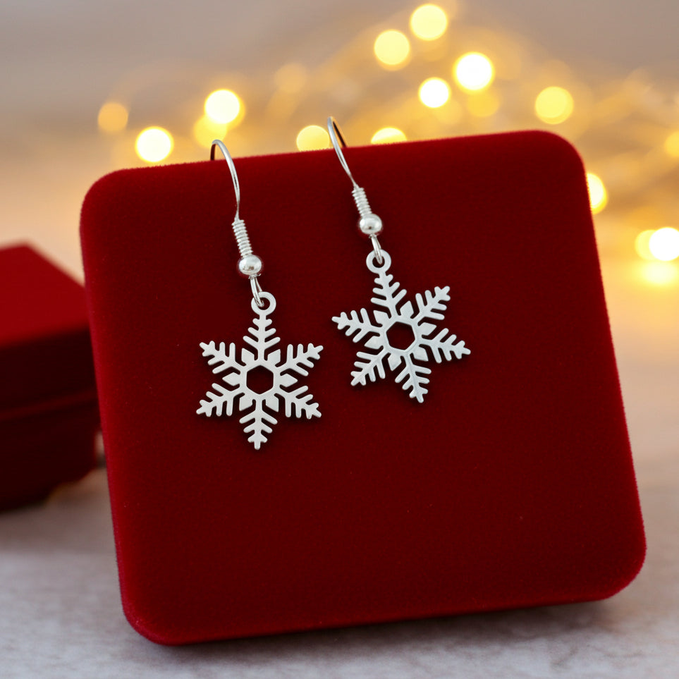 Silver snowflake earrings on a red velvet stand with blurred lights in the background