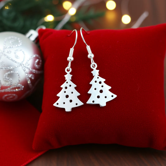 Festive Christmas tree earrings with hooks made from silver stainless steel on red velvet with lights in the background.