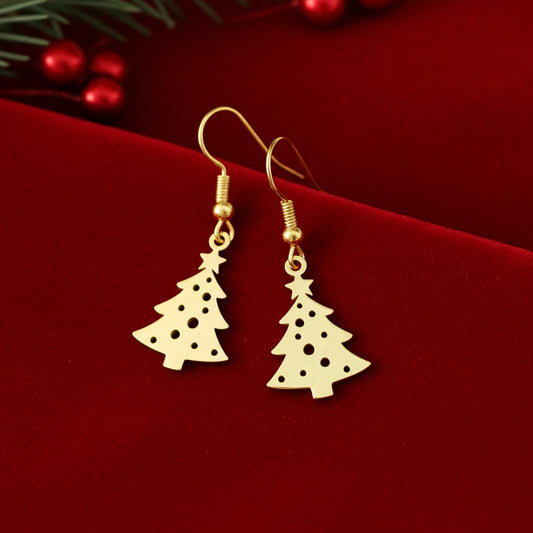 Festive Christmas tree earrings with hooks made from gold stainless steel on red velvet with lights in the background.