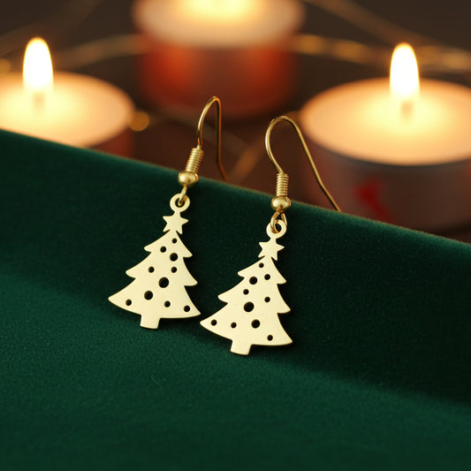 Festive Christmas tree earrings with hooks made from gold stainless steel on green velvet with candles in the background.