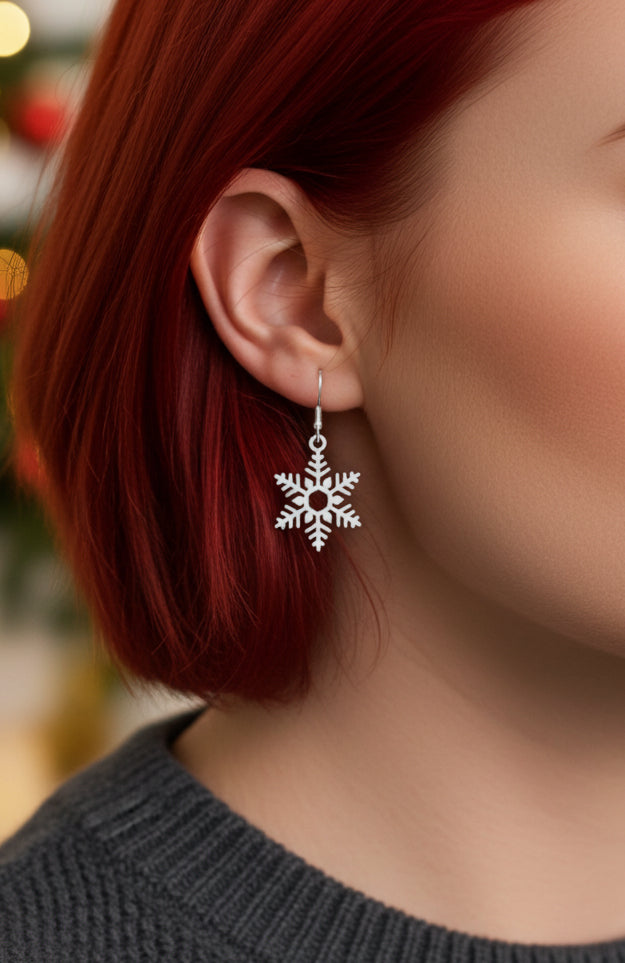 Close-up of a person wearing snowflake earrings with a blurred background