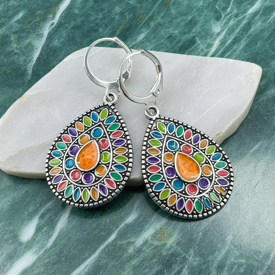 Colorful earrings with a silver setting on a stone surface