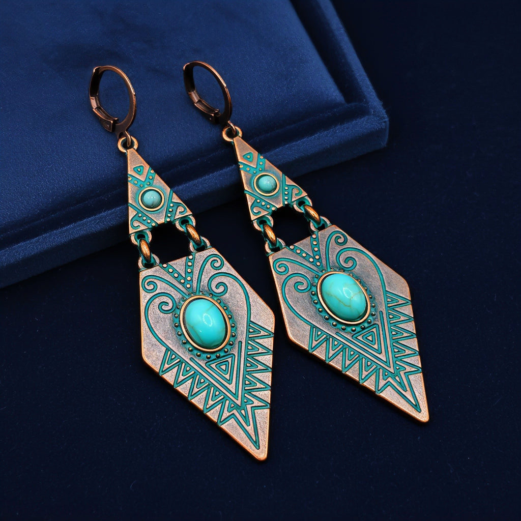 Pair of copper and turquoise earrings with intricate patterns on a dark blue background