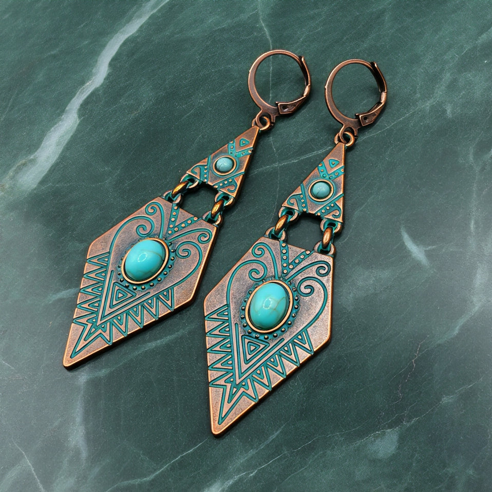 Pair of copper and turquoise earrings on a green marble background