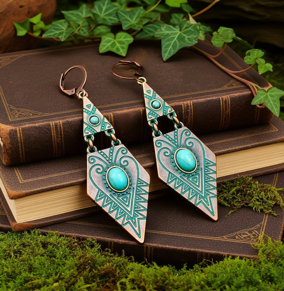 Pair of copper and turquoise ethnic tribal earrings on an old book with green leaves in the background