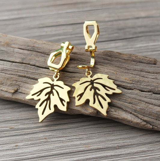 Gold stainless steel leaf earrings with clip ons on a wood background