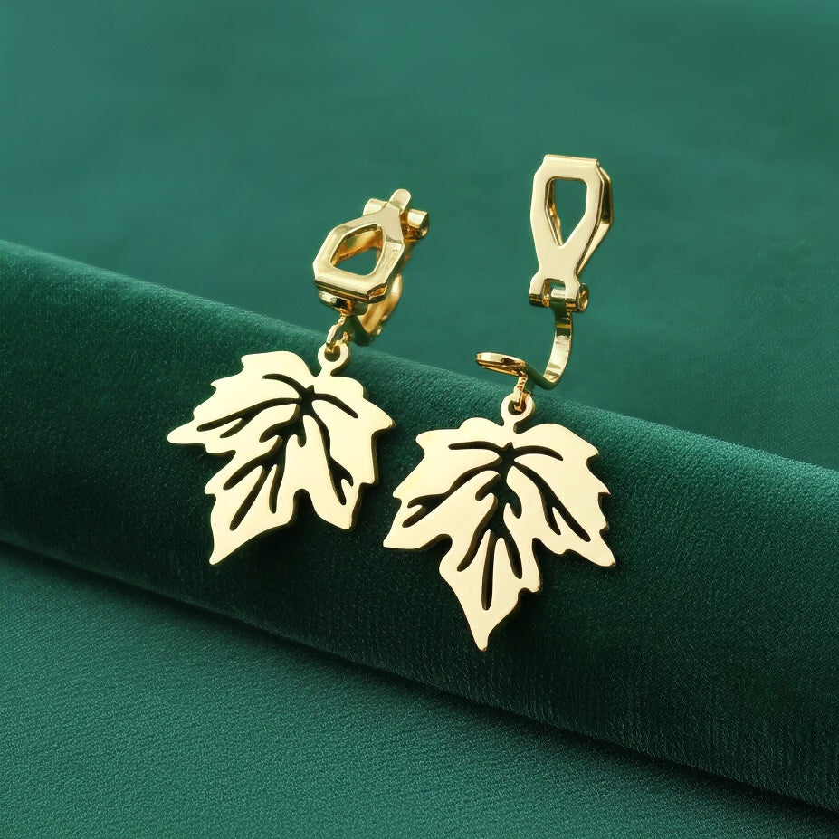 Gold stainless steel leaf earrings with clip ons on a green background