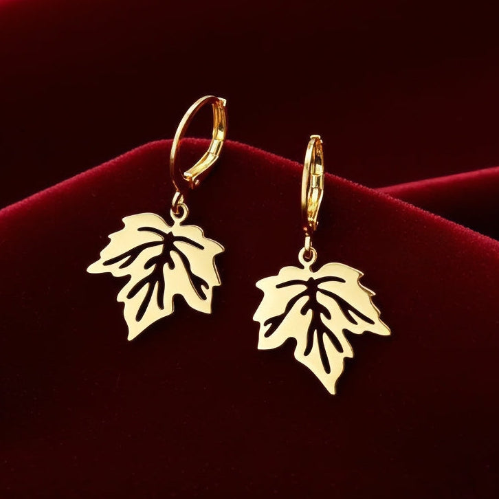 Gold stainless steel leaf earrings with hoops on a red background