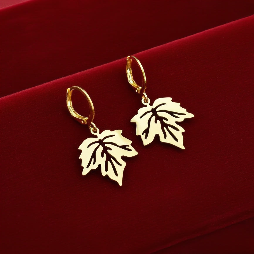 Gold stainless steel leaf earrings with hoops on a red background