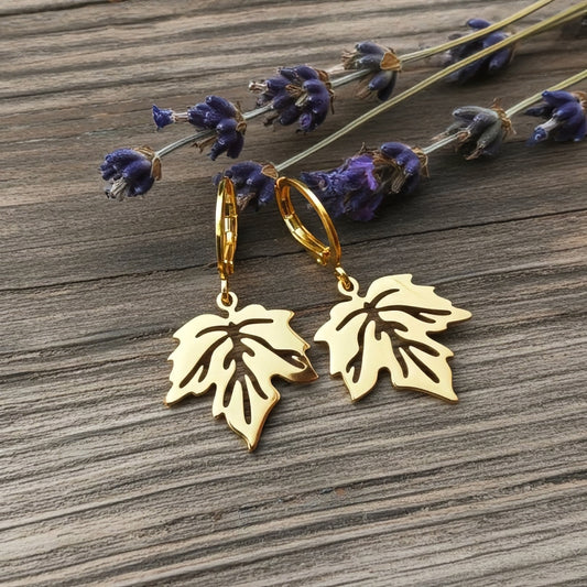 Gold stainless steel leaf earrings with hoops on a wood background with lavender