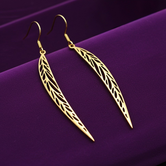 Long pointy gold stainless steel leaf earrings with hooks on a purple background