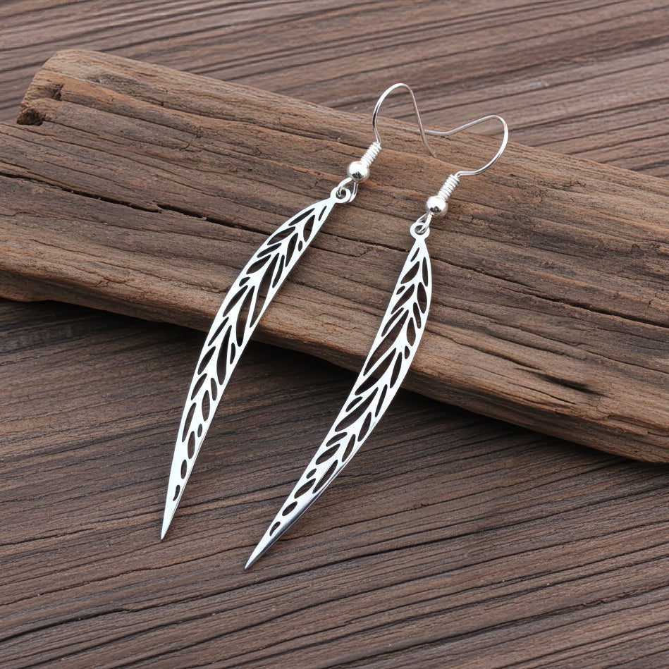 Long pointy stainless steel leaf earrings with silver hooks on a wood background