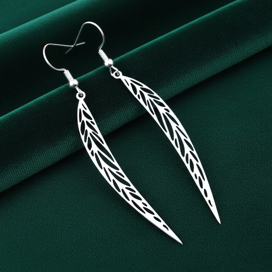 Long pointy stainless steel leaf earrings with silver hooks on a green background