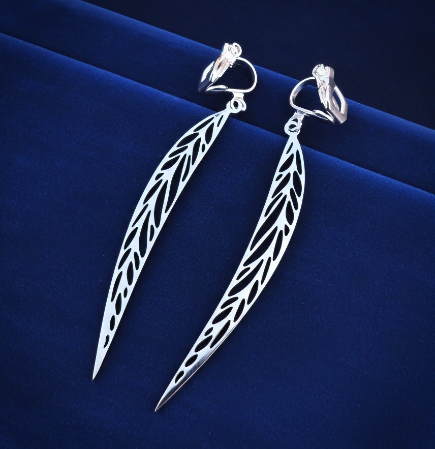 Long pointy stainless steel leaf earrings with silver clip-ons on a blue background 