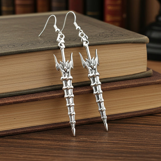 Fantasy silver sword earrings with hooks on a book