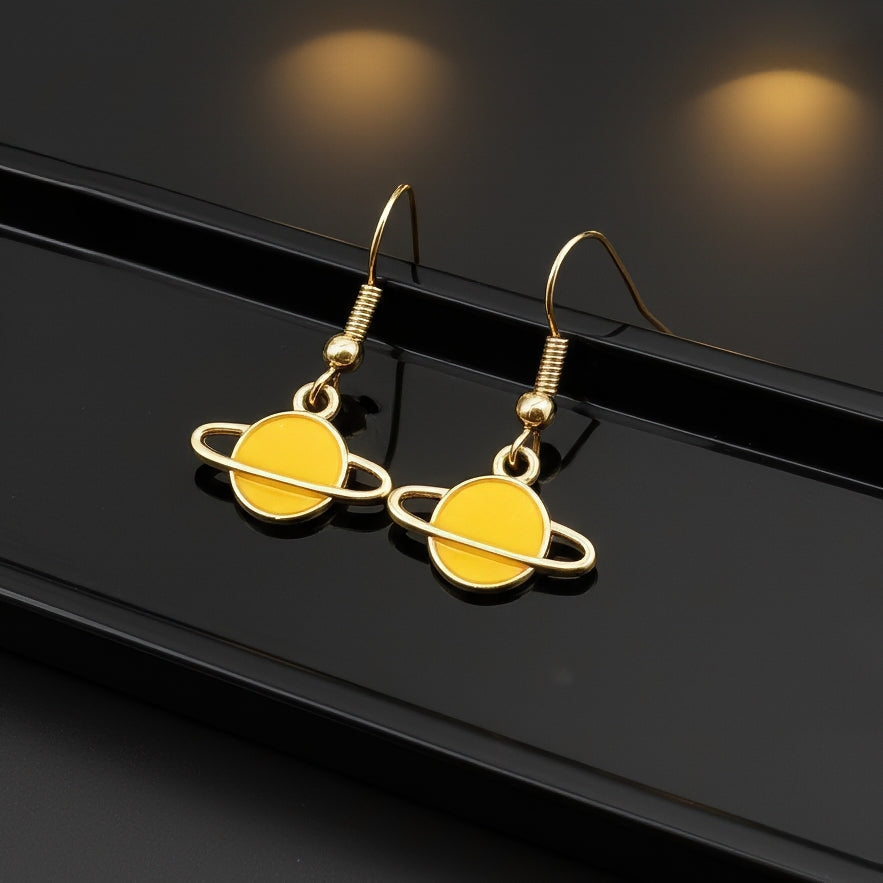Yellow Saturn planet earrings with gold hooks on a black background