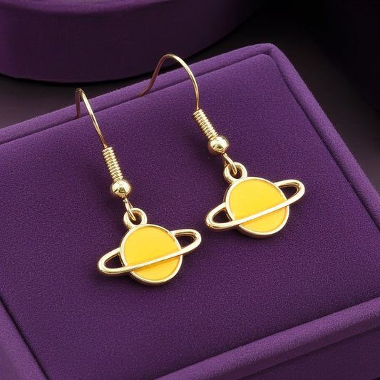 Yellow Saturn planet earrings with gold hooks on a purple background