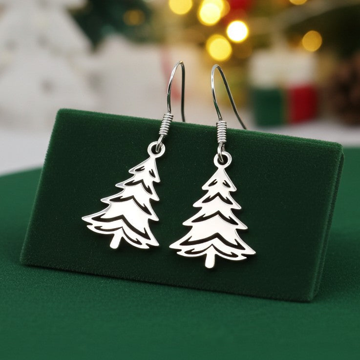 Silver Christmas tree earrings on a green stand with a festive background