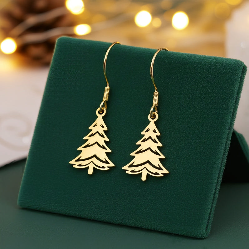 Festive Christmas tree earrings made out of gold stainless steel and hook earrings, on green velvet with lights in the background.