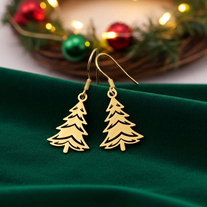 Festive Christmas tree earrings made out of gold stainless steel and hook earrings, on green velvet with lights in the background.