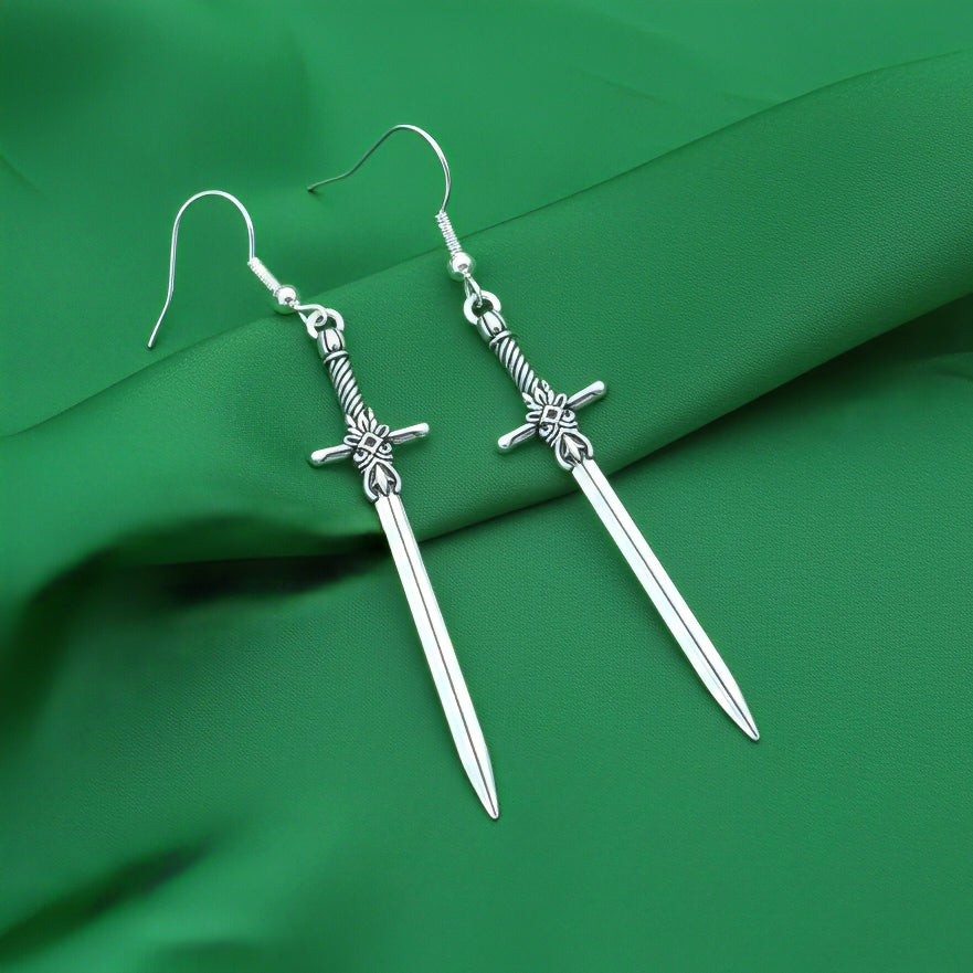 Silver sword earrings on a purple fabric background