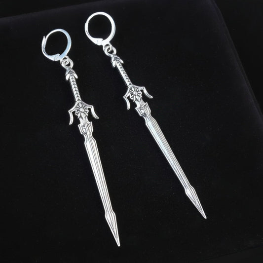 Pair of silver sword earrings with hoops on a black background