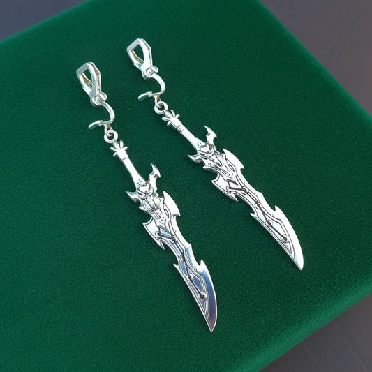 Silver sword earrings with clip ons on a green background