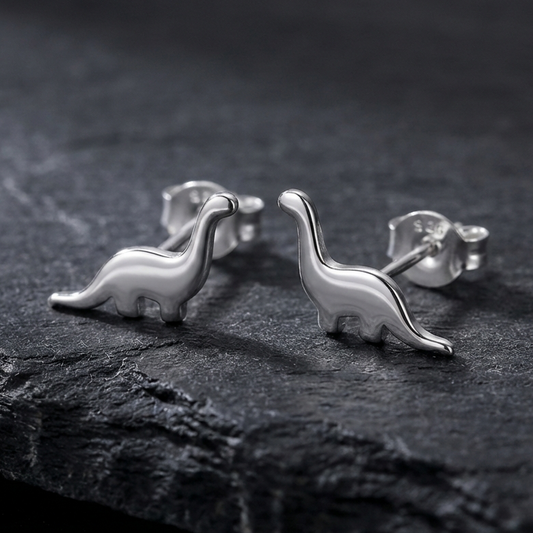 925 Silver dinosaur stud earrings on a dark stone surface