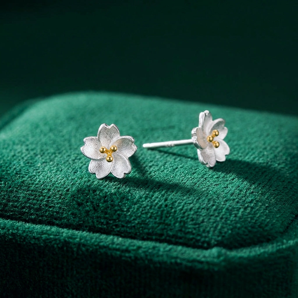Silver flower earrings with gold centers on a green fabric background