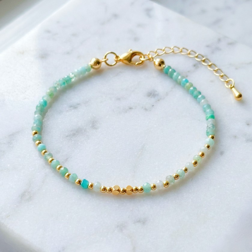 Bracelet with faceted blue aquamarine gemstone beads and gold accents on a marble surface