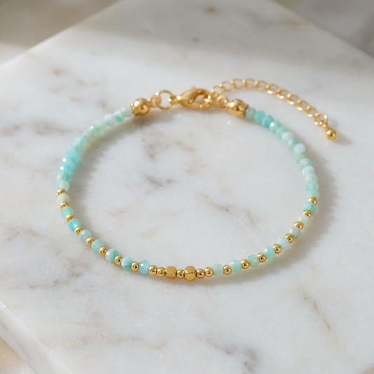 Bracelet with faceted blue aquamarine gemstone beads and gold accents on a marble surface