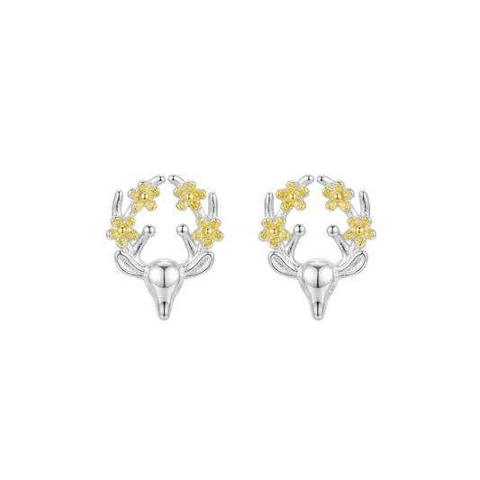 Silver and gold deer shaped earrings with floral details on the antlers on a white background