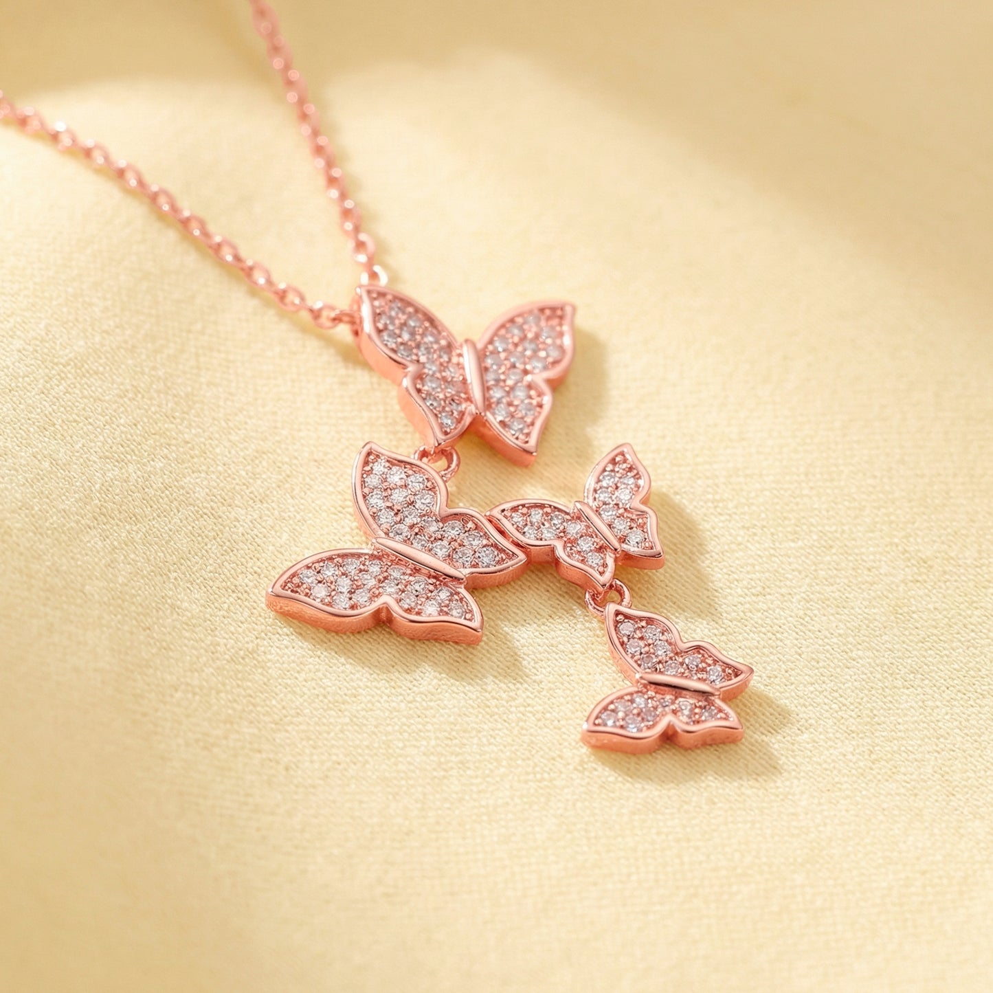 Rose gold butterfly necklace on a beige background