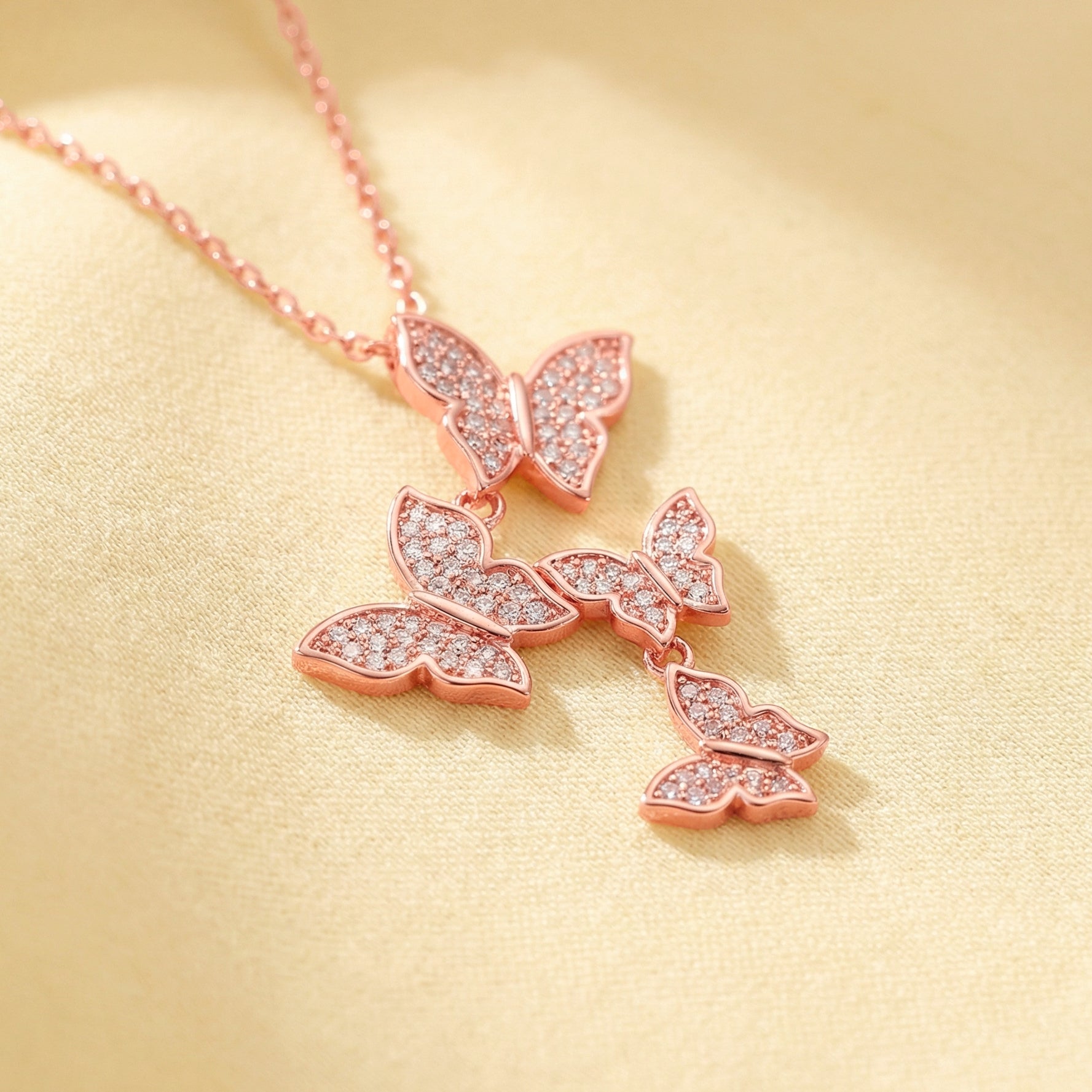 Rose gold butterfly necklace on a beige background