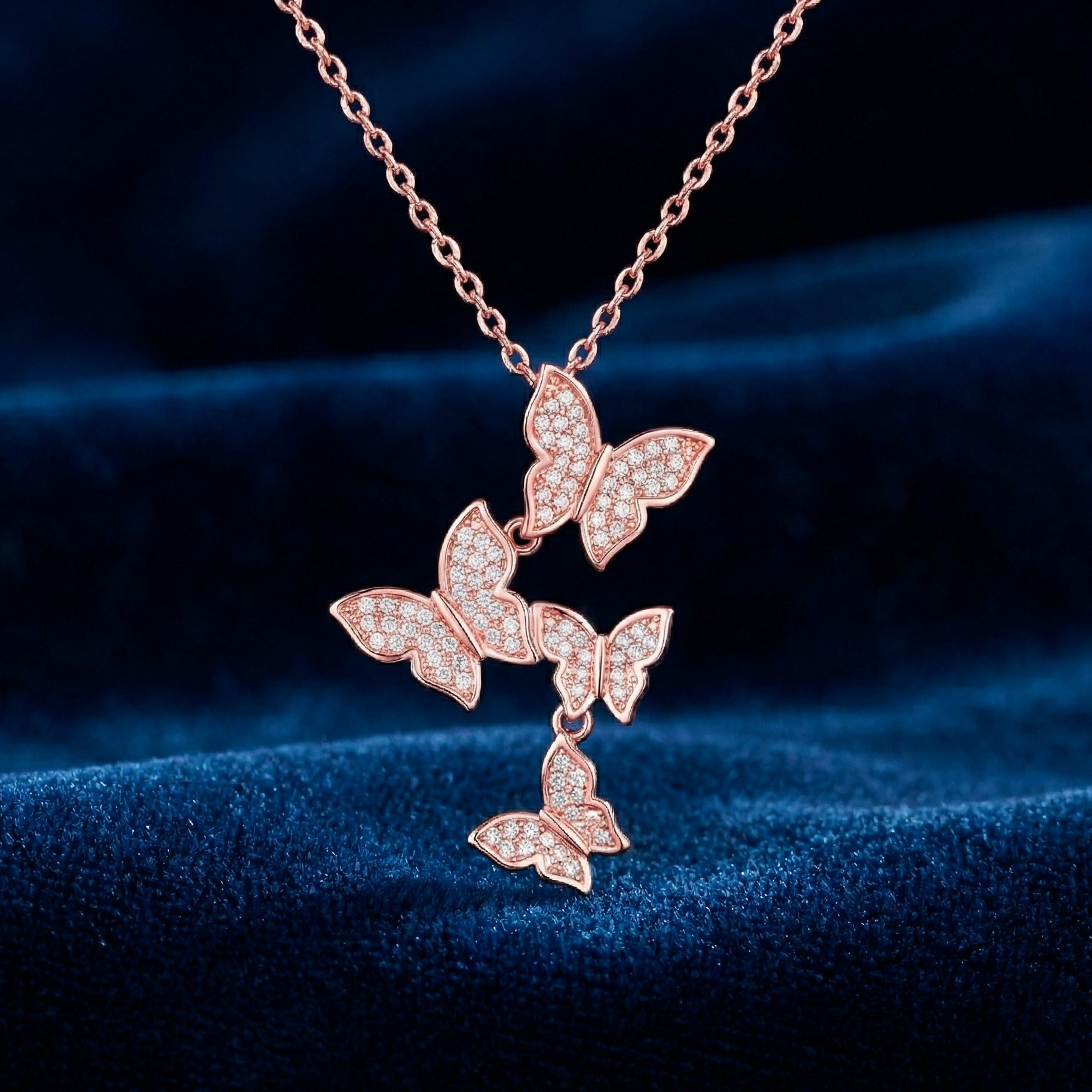 Rose gold butterfly necklace on a dark blue fabric background