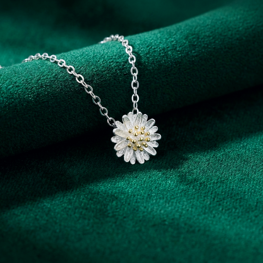 Silver necklace with a floral daisy pendant on a green textured surface
