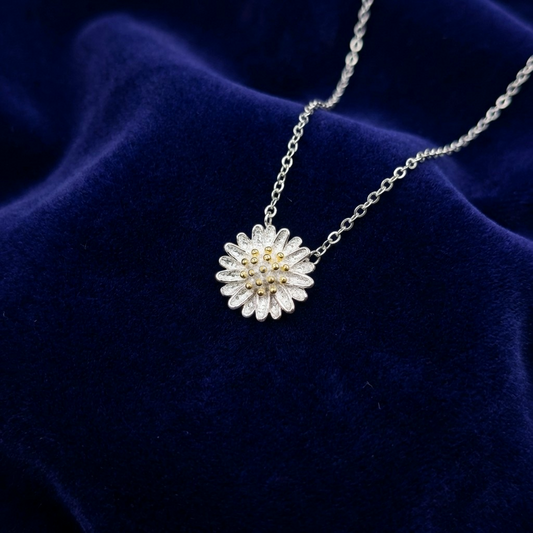 Silver necklace with a floral daisy pendant on a blue velvet background
